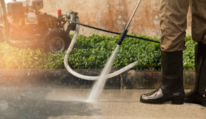 professional using a pressure washer to clean a concrete surface